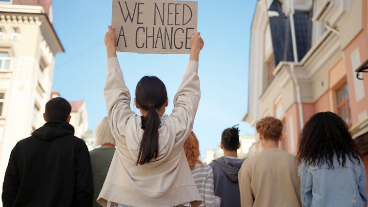 The new monks have their backs behind, and a young white shirt to read read 'we need a change'